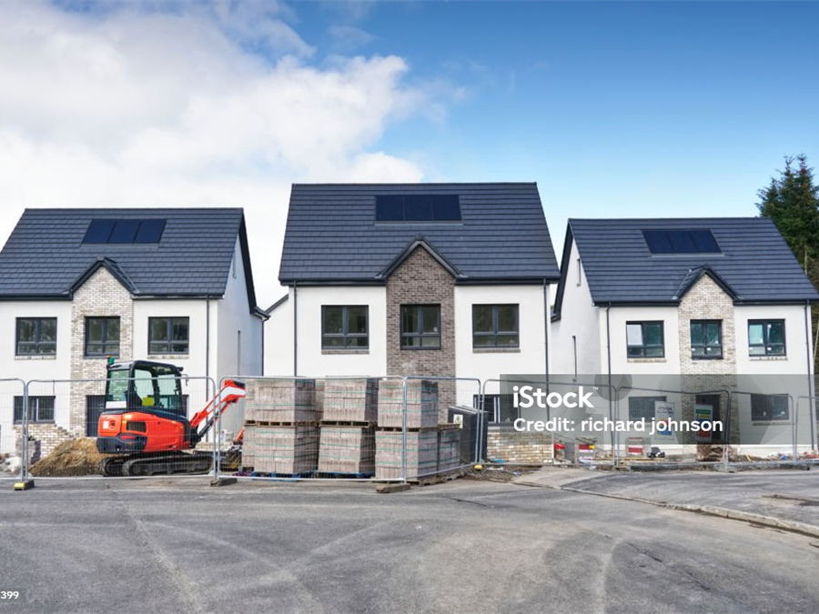 Neubauzeile auf der Baustelle, Rohbau mit Bagger und Materialpaletten