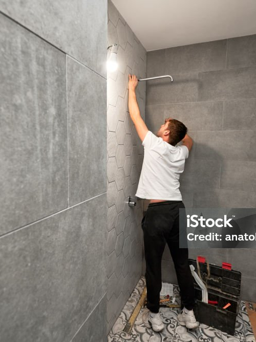 Handwerker bei der Arbeit in einer neu gefliesten Dusche